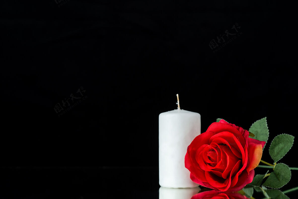 花黑上有红玫瑰的白蜡烛的正视图蜡烛玫瑰花