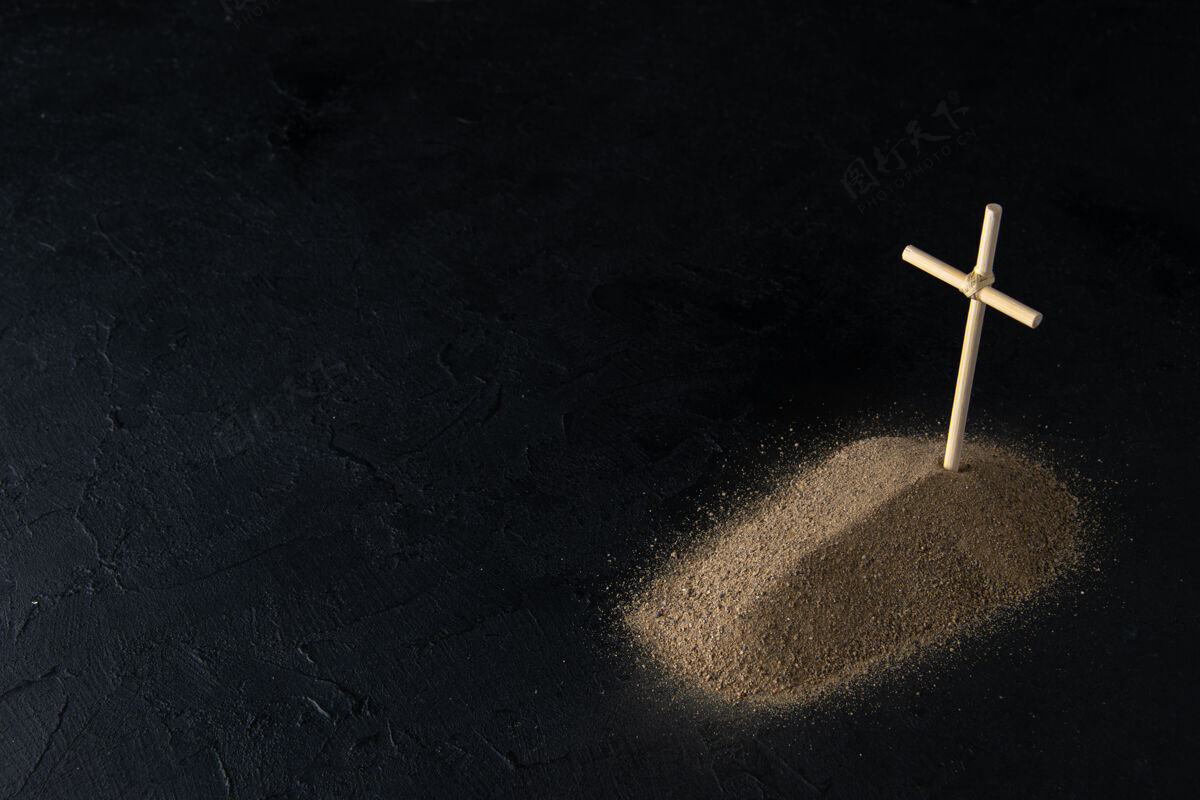 葬礼从沙子上看到的小坟墓的正面图 黑色的十字架火柴十字架纹理