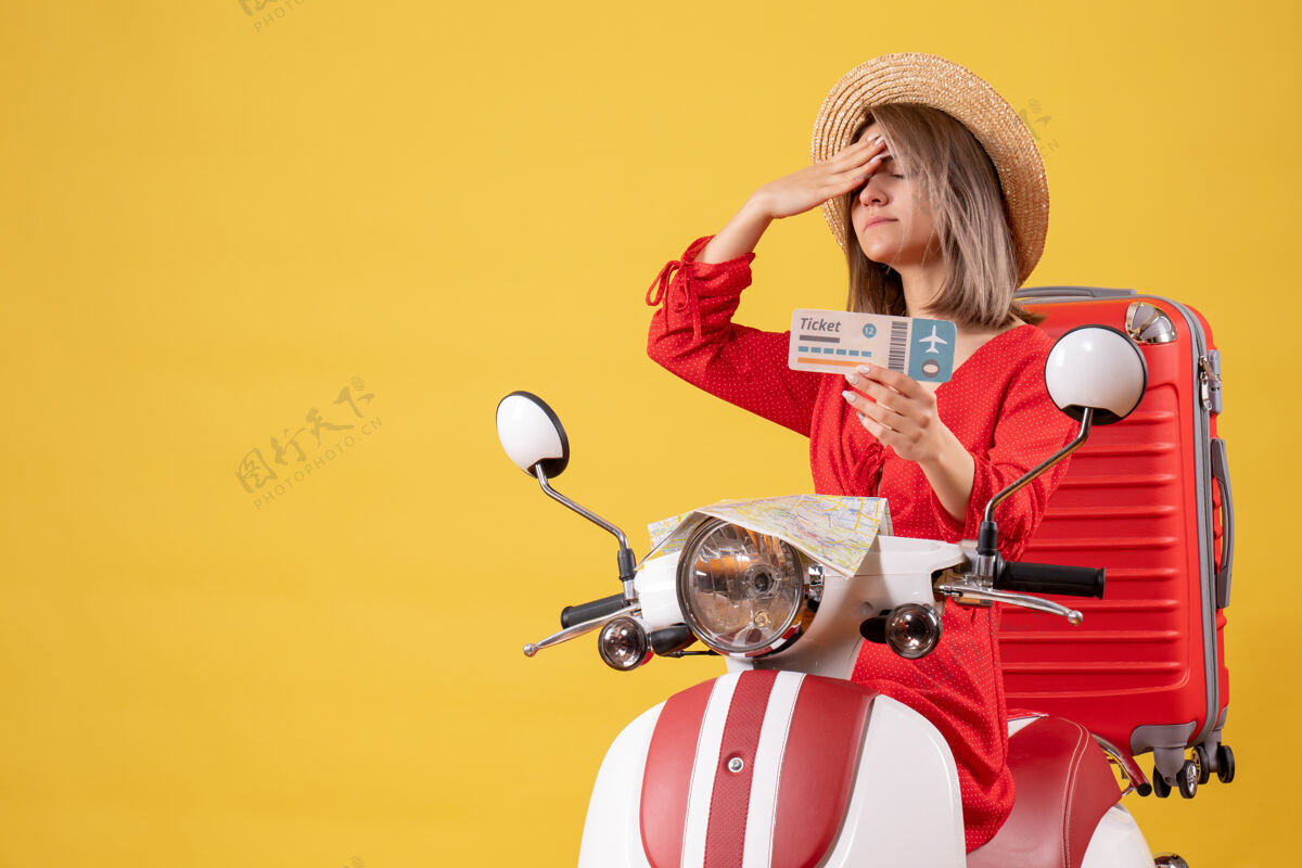冒险正面图：穿着红裙子的年轻女士 头枕着轻便摩托车票旅游成人