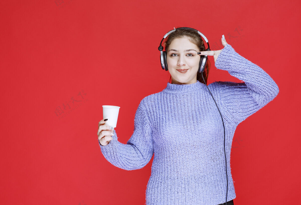 聪明戴着耳机拿着咖啡杯思考的女孩员工女人表演