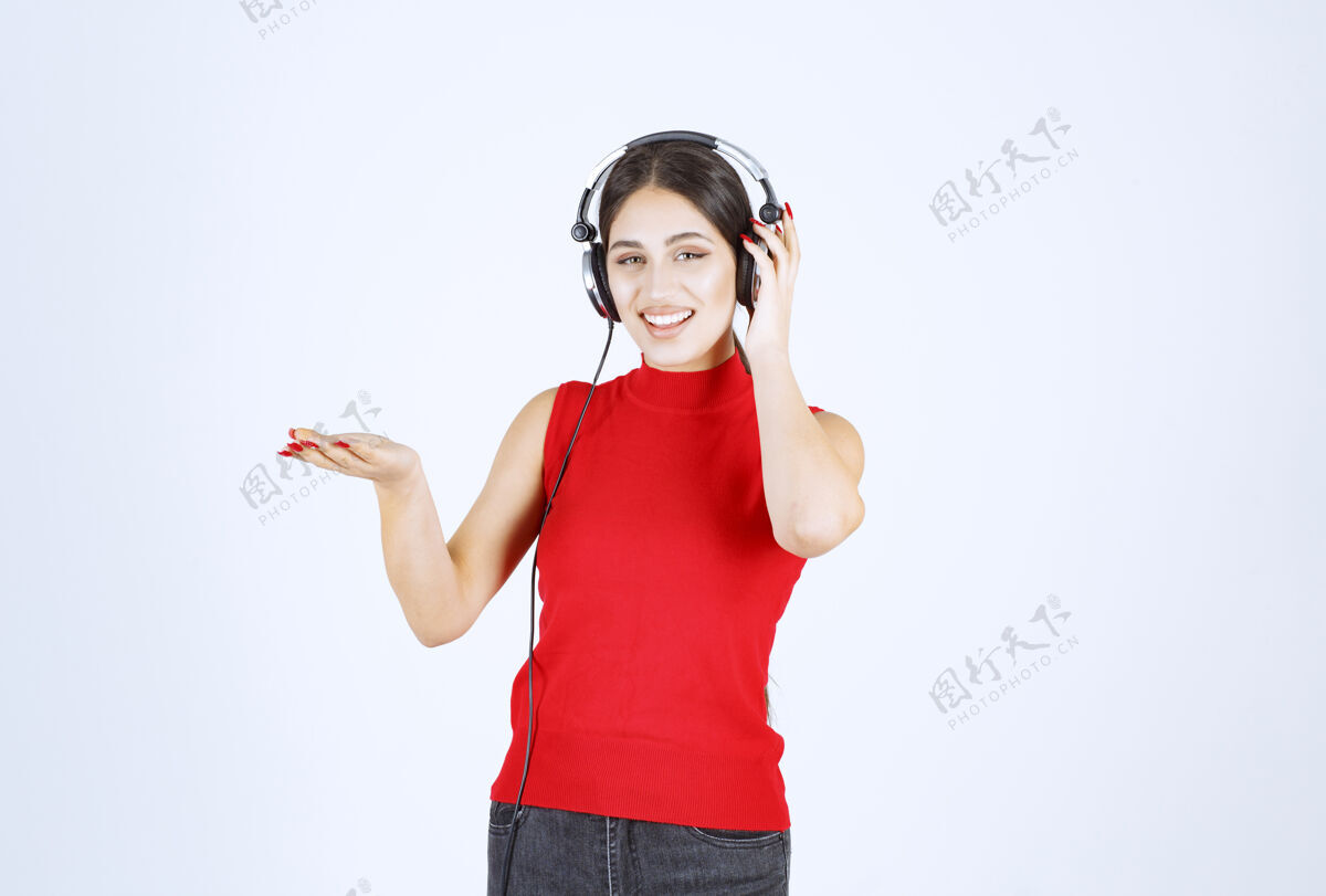 休闲穿着红衬衫的Dj女孩 戴着耳机 手上拿着什么东西或是什么东西工作人员服装人