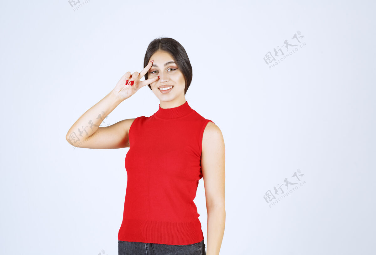 符号穿红衬衫的女孩透过手指看女人害羞女性