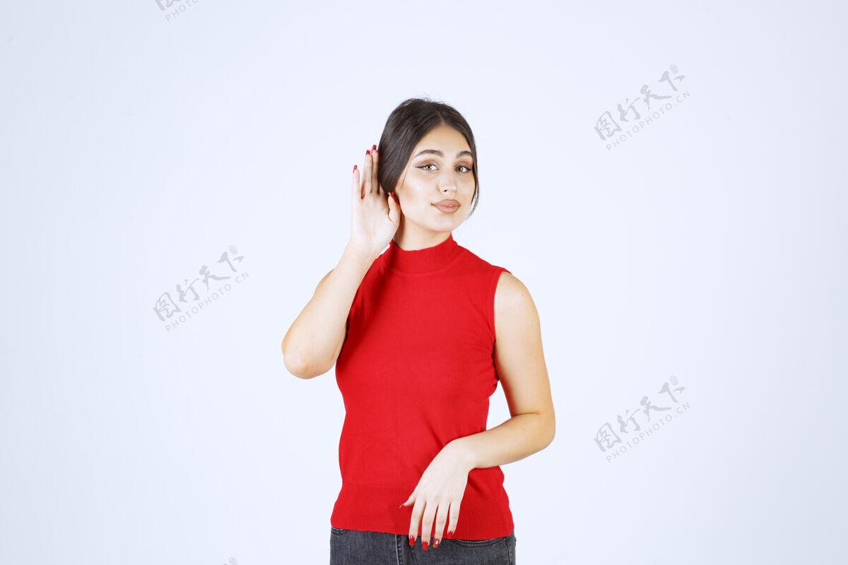 员工穿红衬衫的女孩指着耳朵想好好听人女人成人