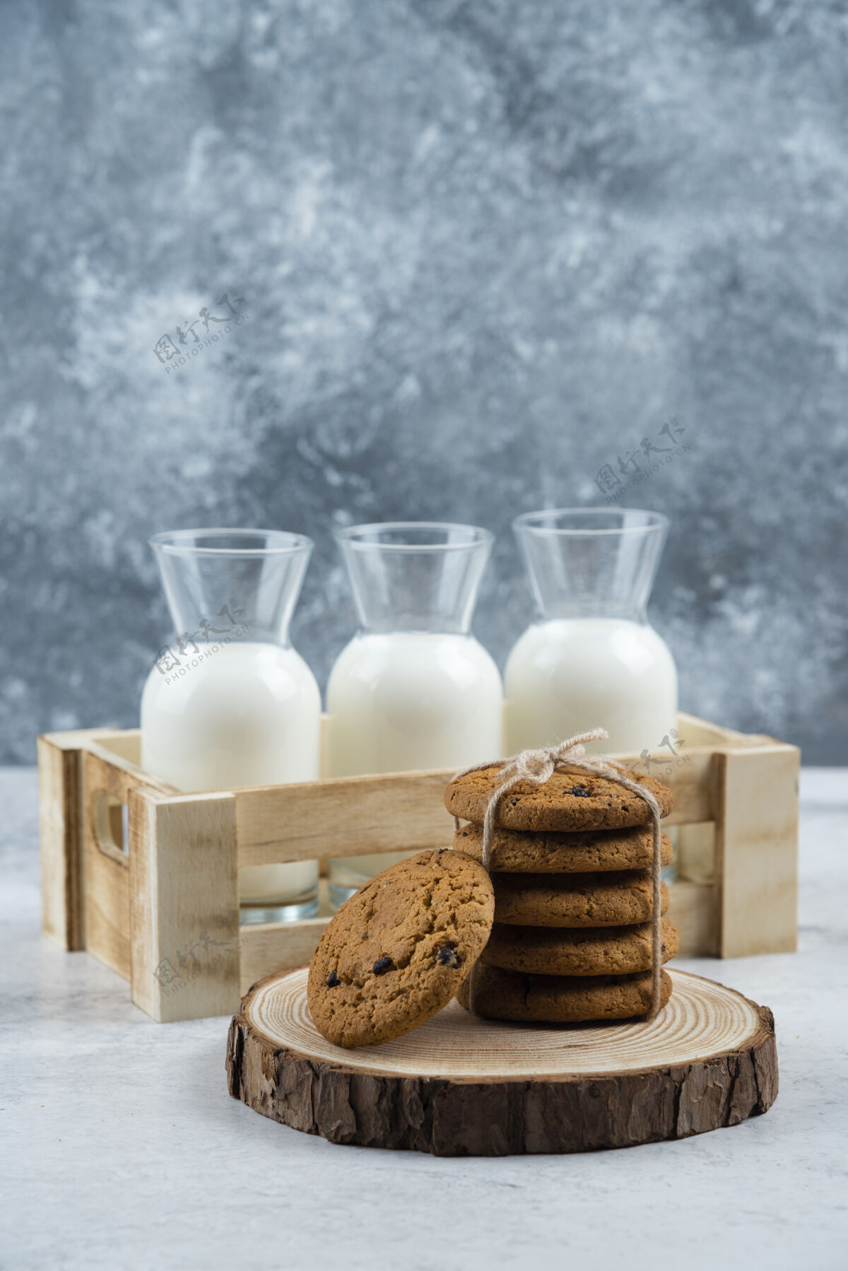 牛奶三杯牛奶和一堆饼干放在大理石桌上木头面包房绳子