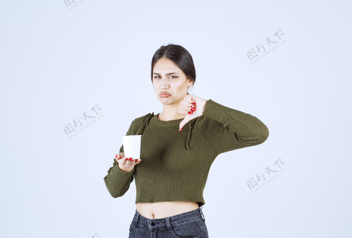 年轻黑发女人拿着塑料杯 大拇指朝下持有肖像成人