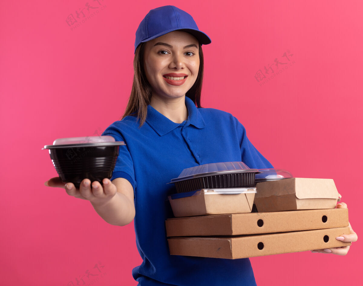 粉色一个穿着制服 面带微笑的漂亮女送货员拿着比萨饼盒上的食品容器和食品包装食物容器送货