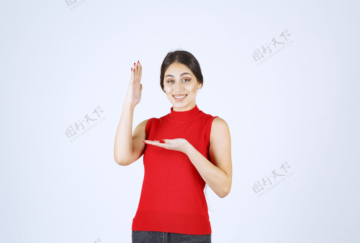 人穿红衬衫的女孩在她张开的手上展示着什么年轻人雇员女人
