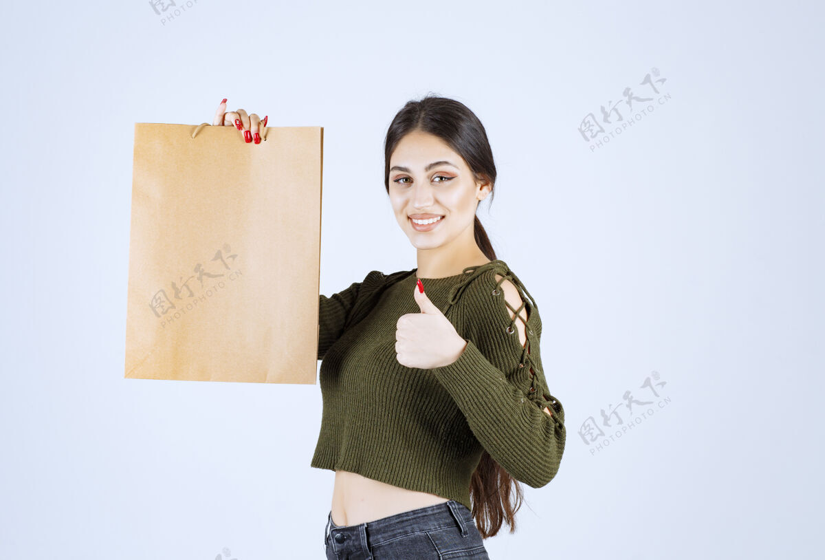 女人年轻女子拿着纸袋 在白色背景上竖起大拇指年轻模特人