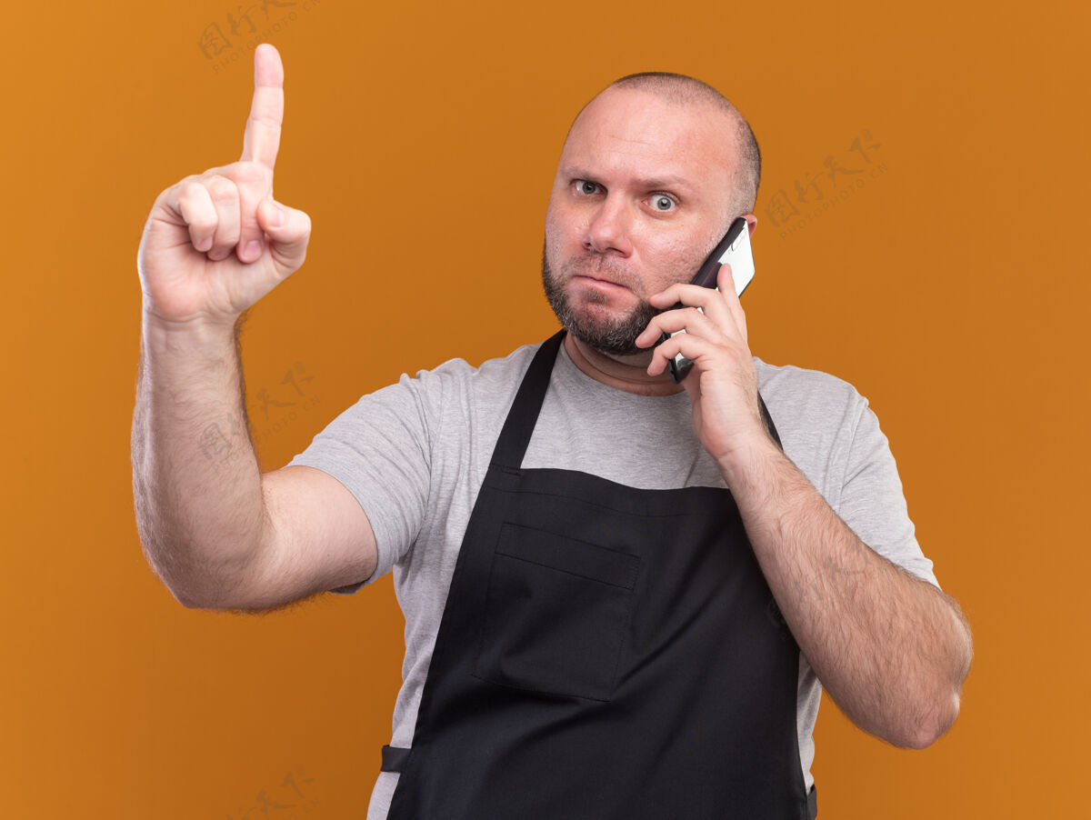 说话严苛的中年男理发师穿着制服对着电话指着隔离在橘色墙上的上脸人姿势