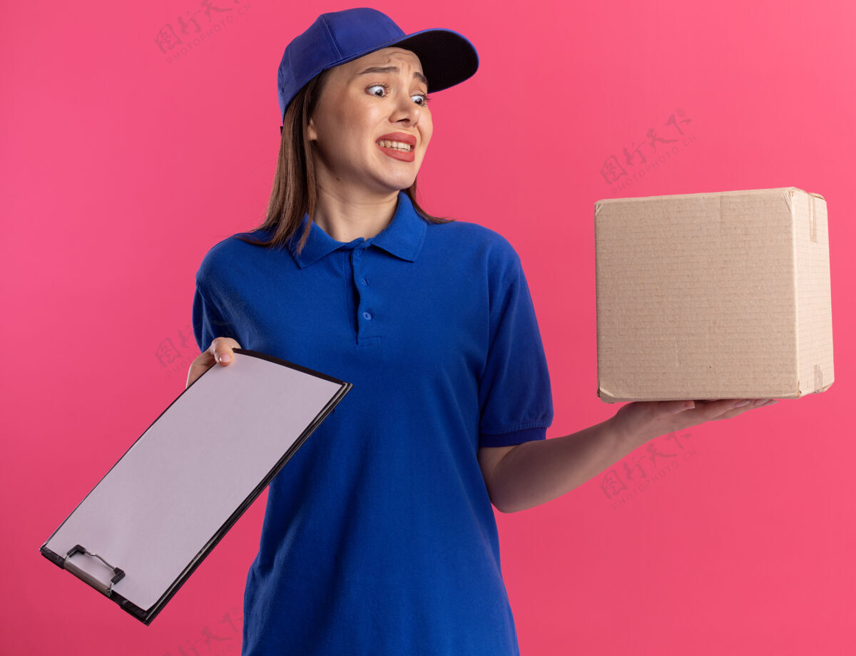 焦虑一个穿着制服 心急如焚的美女拿着剪贴板 看着卡片盒制服粉色送货