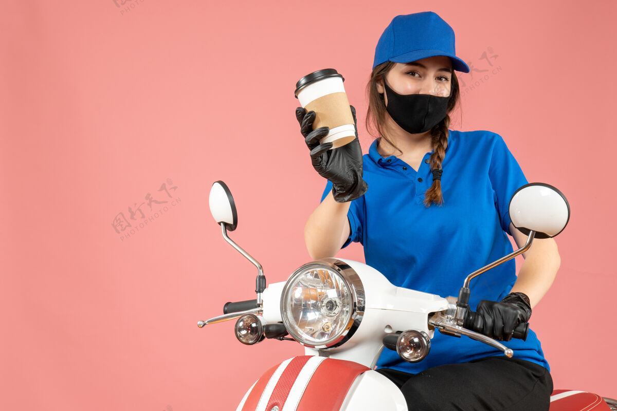 背景俯视图：勤劳的女快递员戴着黑色医用面罩和手套 在桃色背景下递送订单穿人修理工