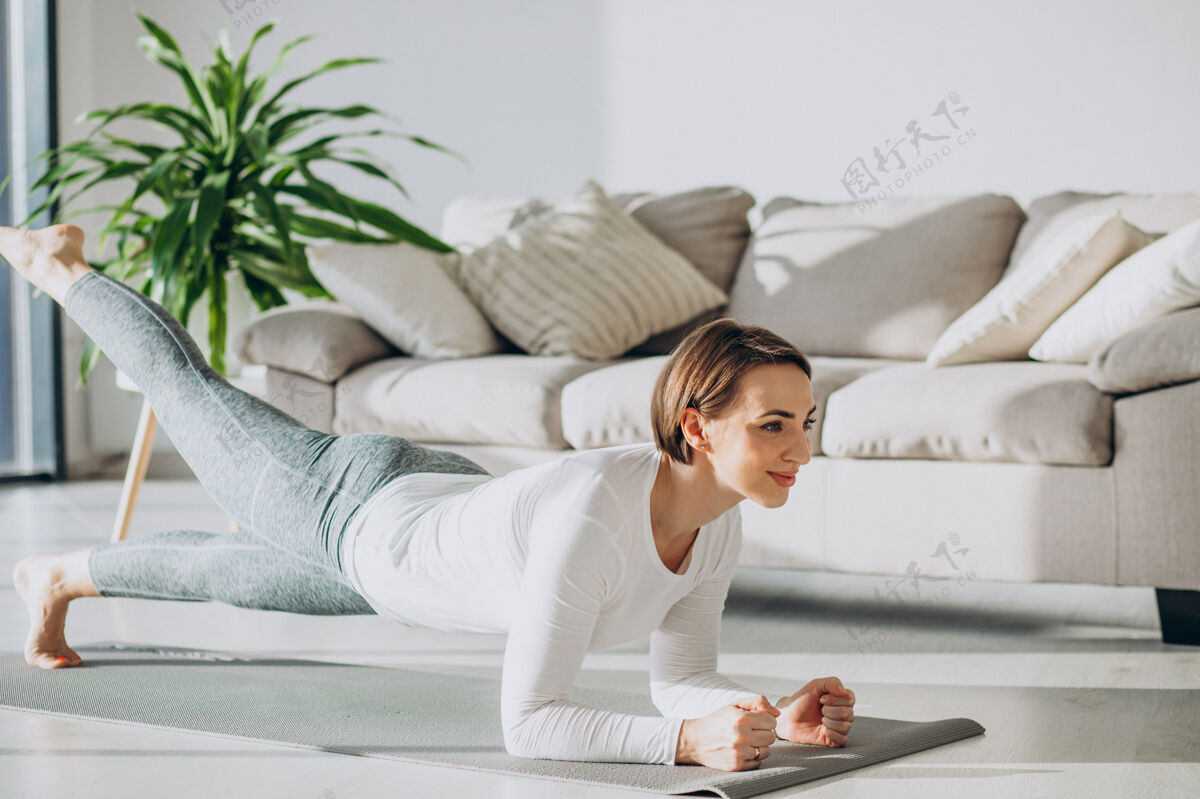 女性年轻女子在家里的垫子上练习瑜伽美丽成人瑜伽健康运动