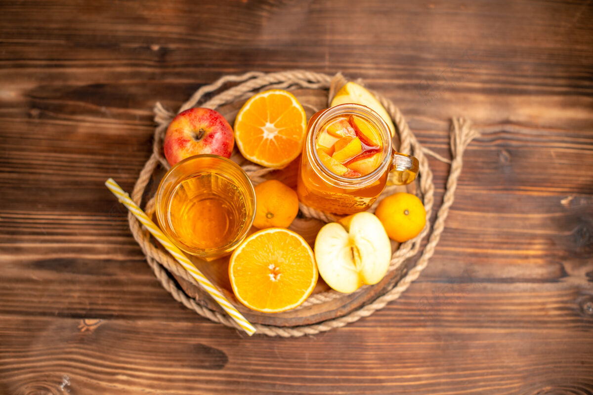 管俯瞰图有机新鲜果汁在一个瓶子和玻璃管和水果提供了一个砧板和棕色的木桌上新鲜玻璃柑橘