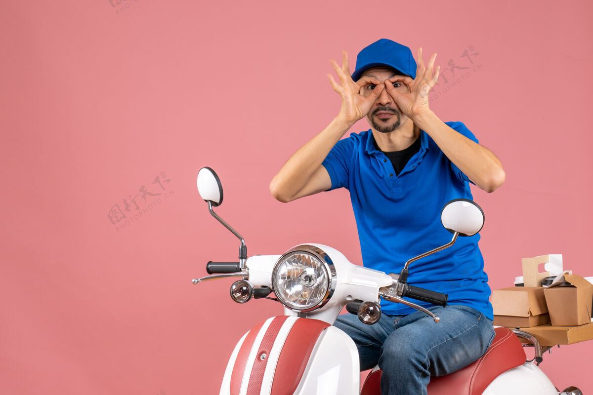 坐着快递员戴着帽子坐在滑板车上做着眼镜的姿势 两边都是粉色背景手势穿摩托车