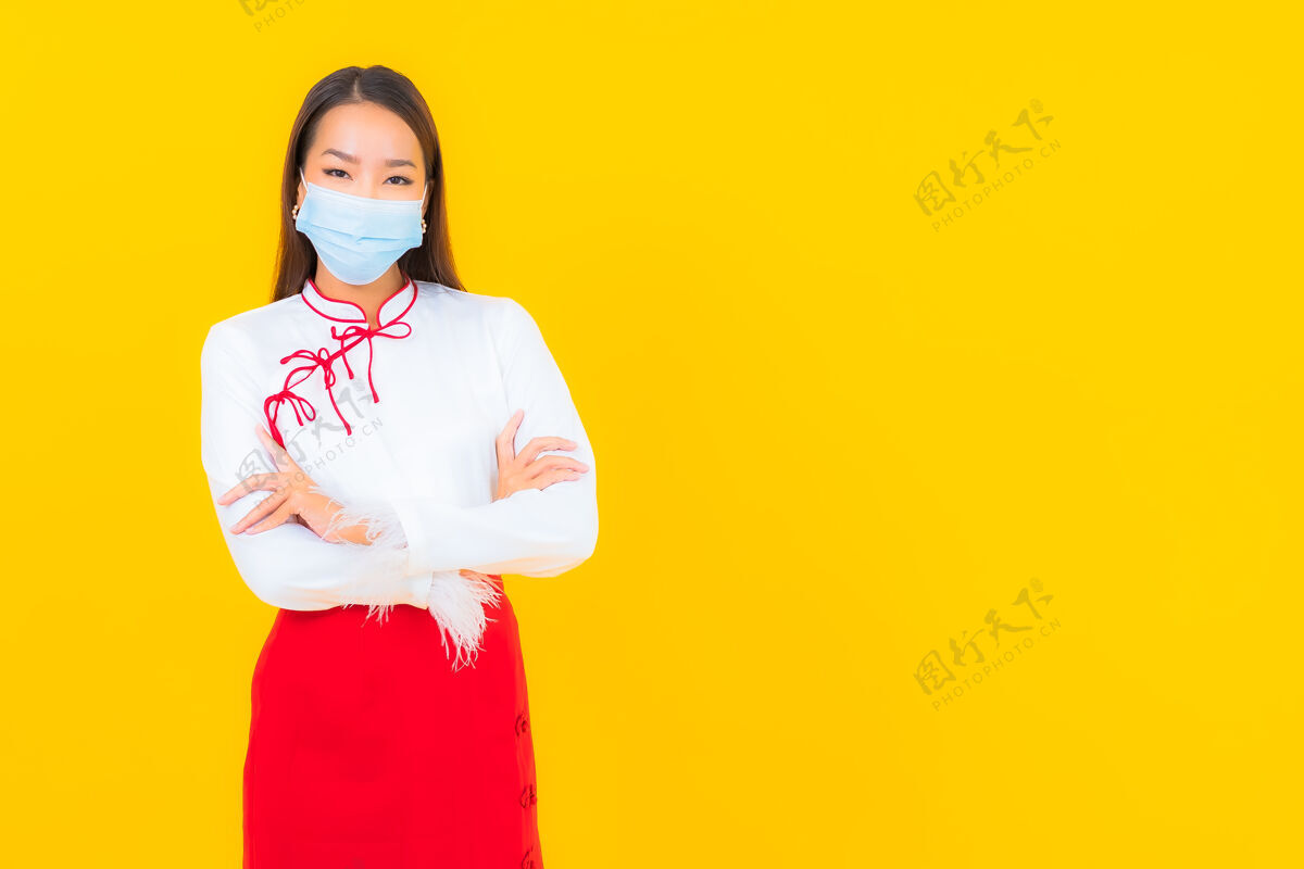 女性肖像美丽的亚洲年轻女子戴上口罩 用酒精凝胶保护黄色的covid19流感电脑清洁