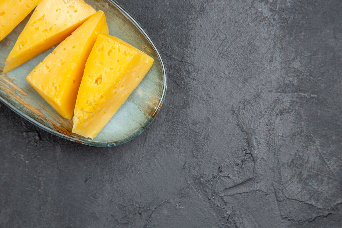 水果右边蓝色盘子上美味的黄色切片奶酪俯视图 黑色背景背景正餐壁板