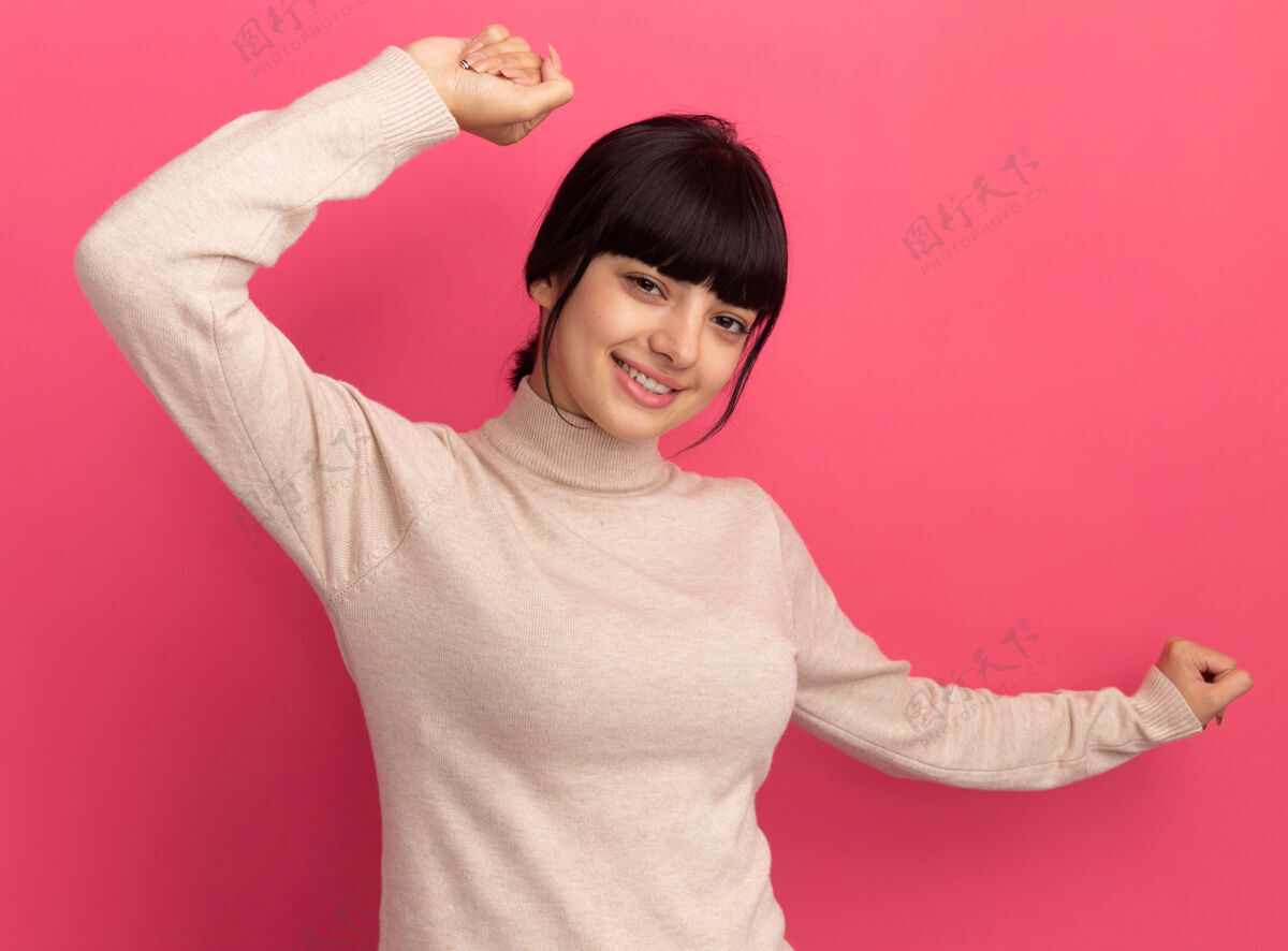 女孩高兴的年轻黑发高加索女孩举起拳头站起来举起手来站起来粉红