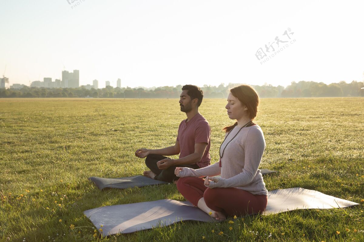 水平男女在户外瑜伽垫上冥想的侧视图女人男人思想