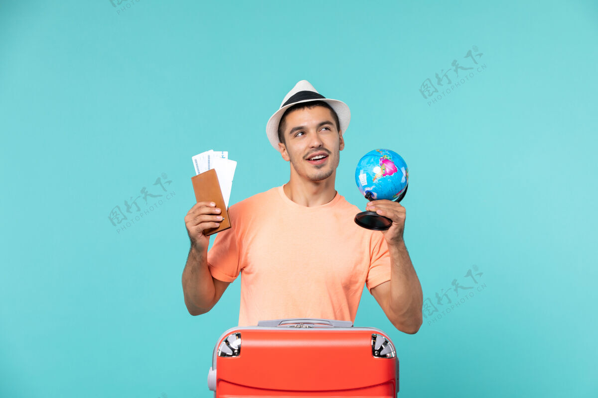举行正面图男性在度假时拿着小地球仪和蓝色的门票航行蓝色旅行