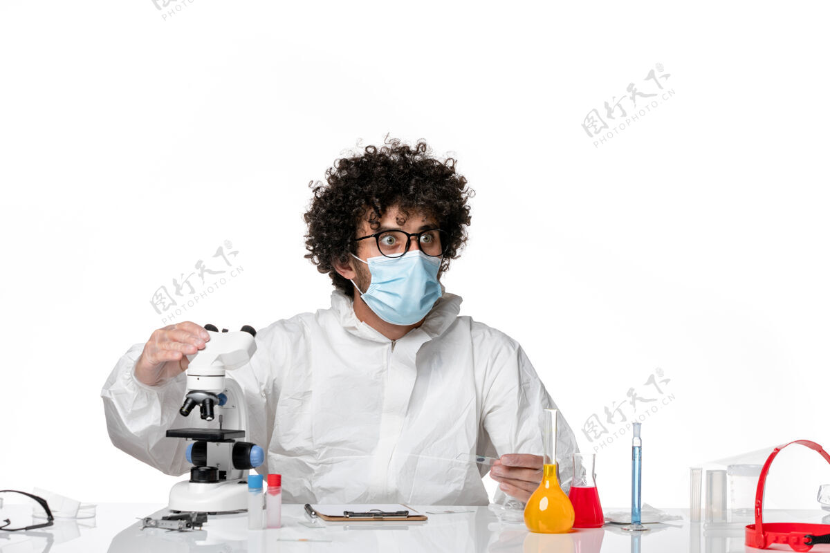 视图男医生穿着防护服 戴着口罩 用显微镜对着白色套装健康病毒