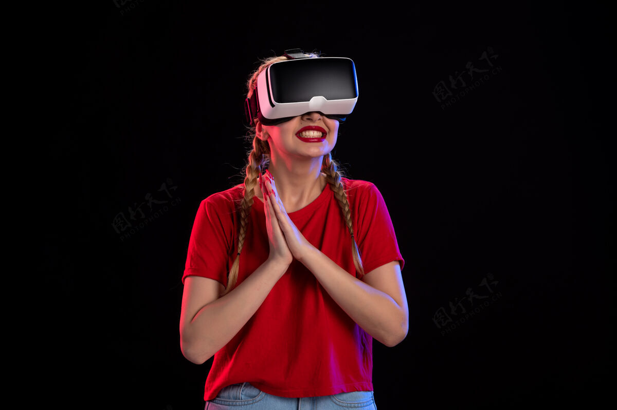 黑暗年轻女性在黑暗的墙上玩虚拟现实的正面图游戏成人肖像