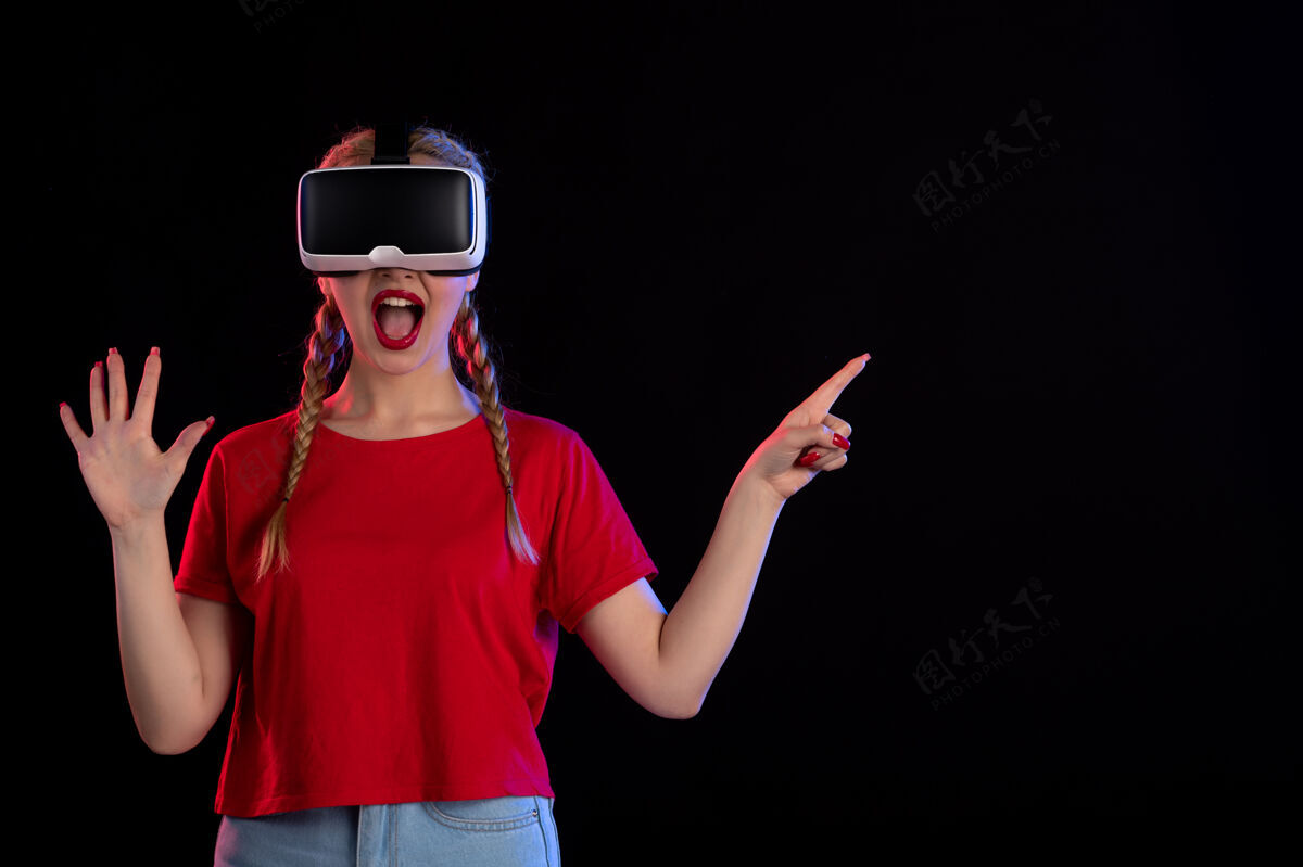 正面年轻女性在黑暗的墙上玩虚拟现实的正面图视图虚拟现实年轻女性