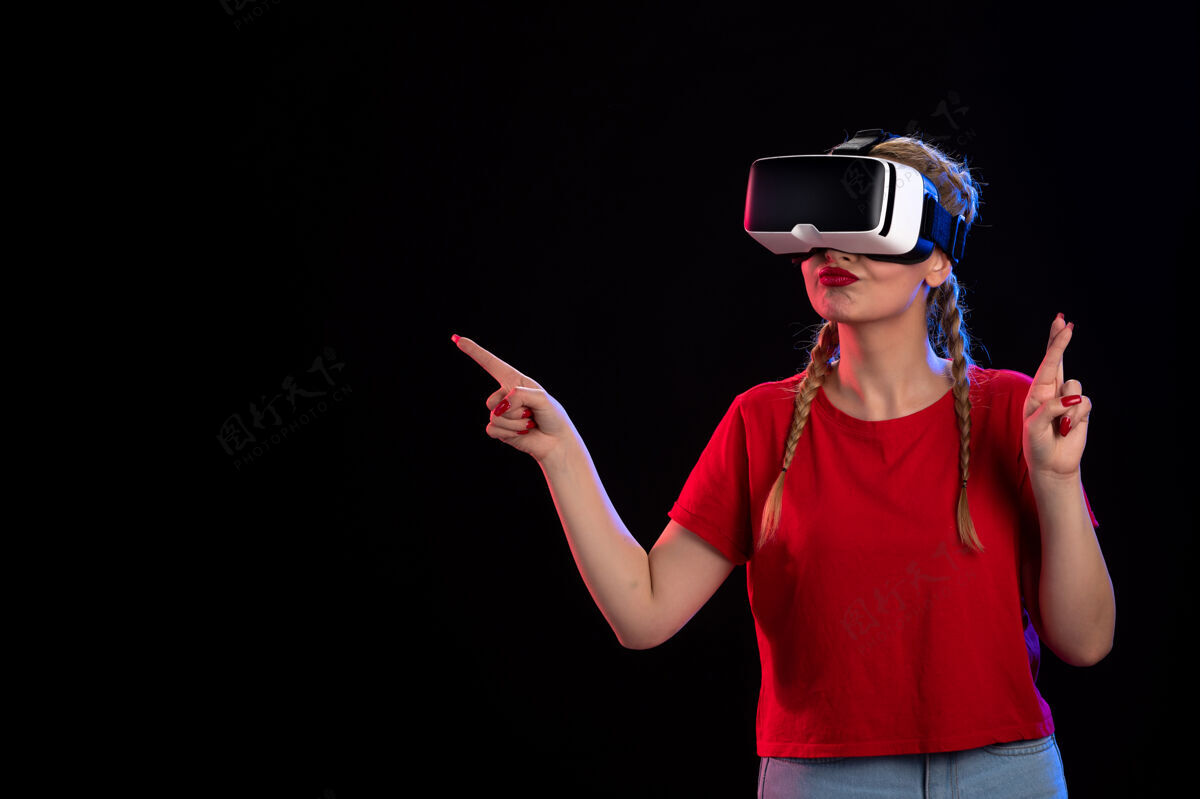 成人年轻女性在黑暗的墙上玩虚拟现实的正面图视觉人物黑暗