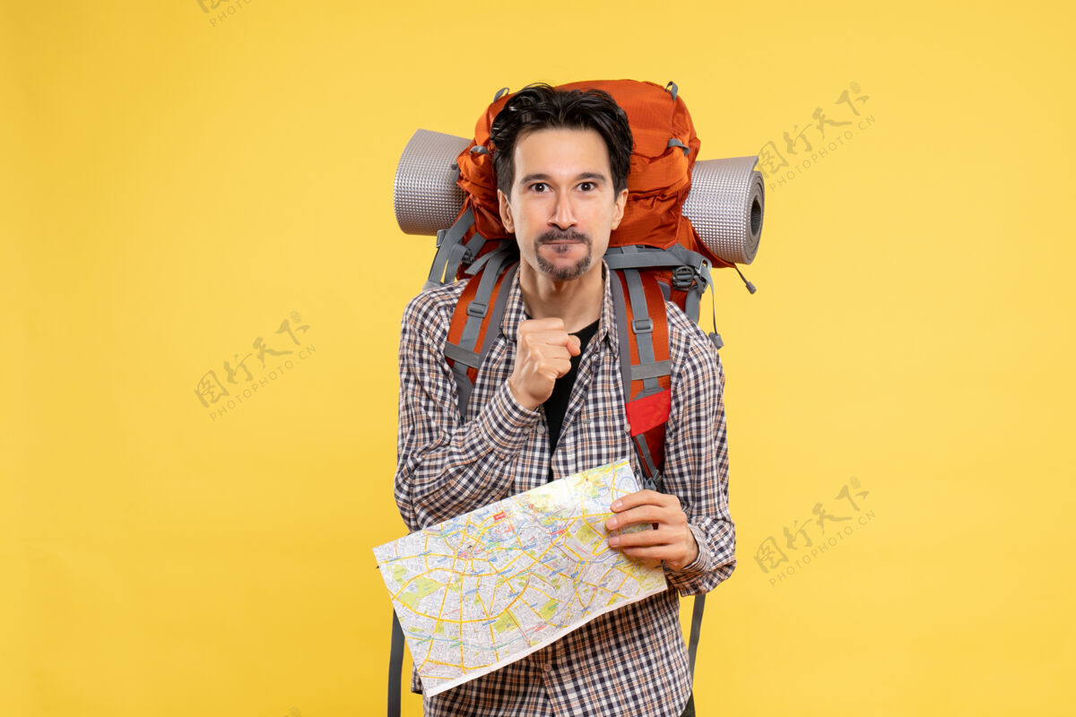 徒步旅行正面图年轻男性徒步旅行 背着背包 拿着地图 背景是黄色的旅行 空气自然公司校园森林的颜色地图年轻的男性举行