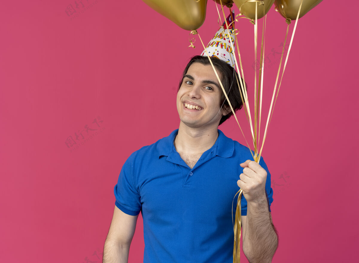 男人笑容可掬的高加索帅哥戴着生日帽手持氦气球粉色生日帽子