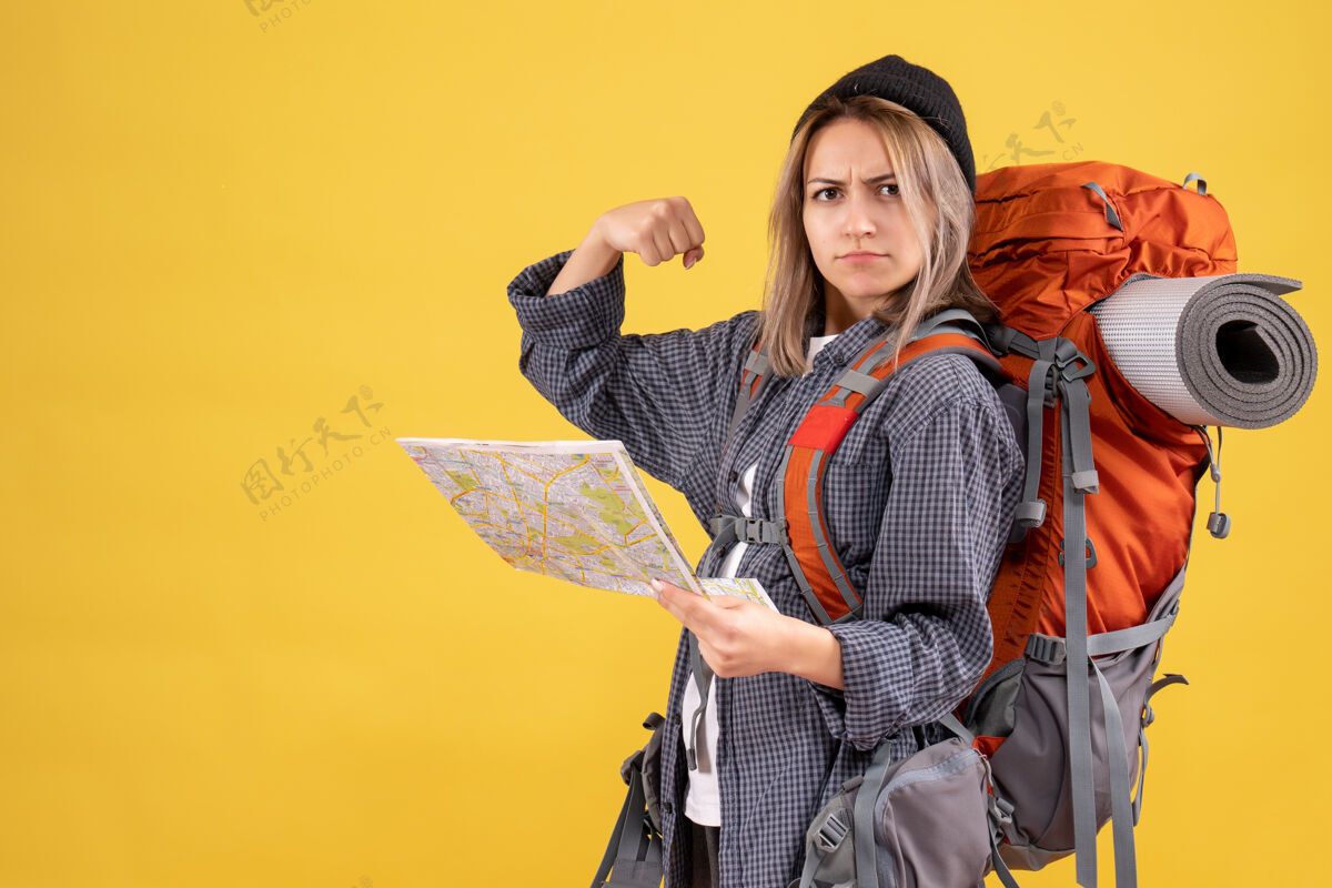 女旅行者旅行妇女背着背包拿着地图显示手臂肌肉地图时尚脸