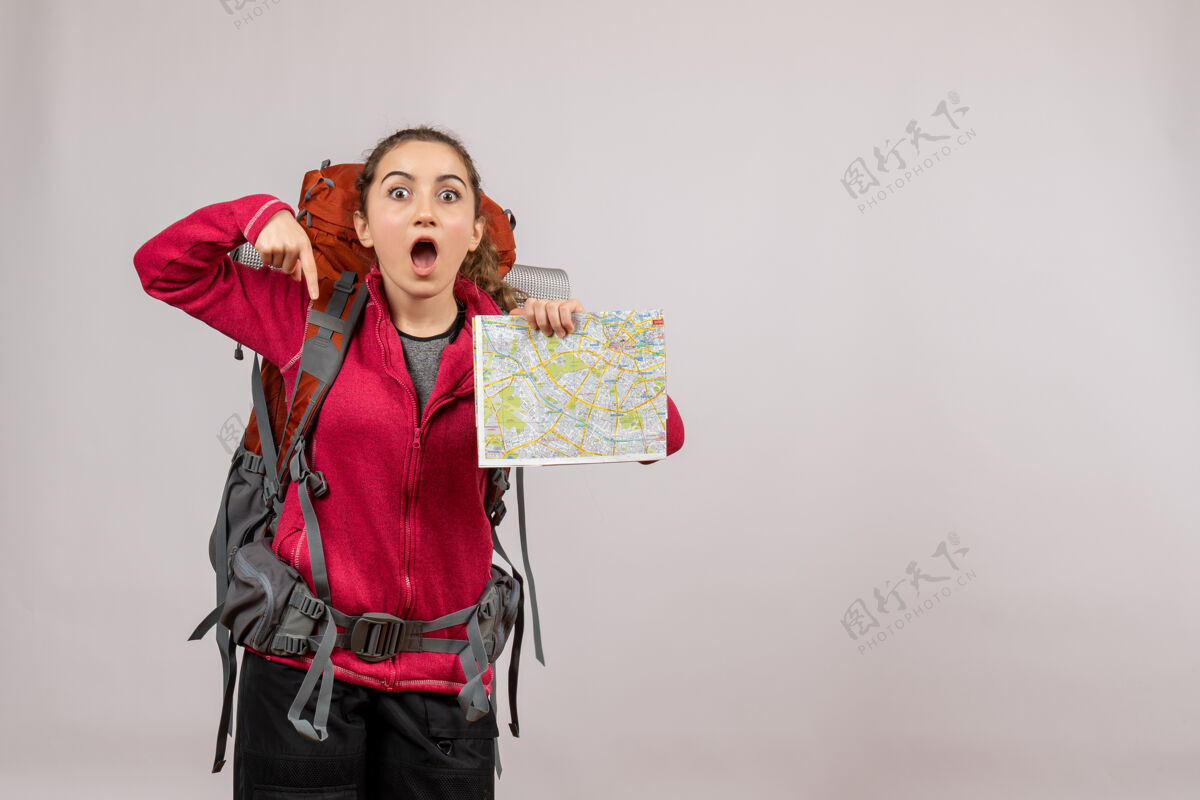 成人惊讶的年轻旅行者背着大背包拿着地图在灰色的孤岛上包大时尚