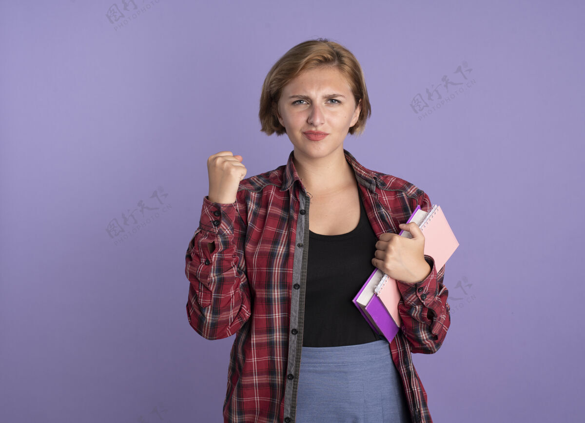 持有自信的年轻斯拉夫女学生握紧拳头拿着书和笔记本笔记本女孩年轻