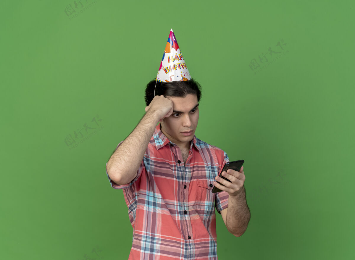 电话帅气的白种人戴着生日帽 手放在额头上 拿着手机看着空间生日额头