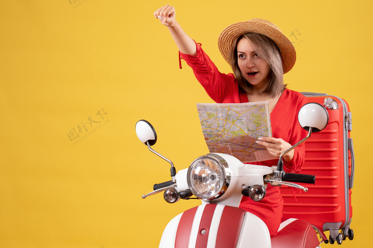 坐着穿着红裙子的漂亮女孩 骑着轻便摩托车 提着大箱子 拿着地图车辆摩托车漂亮女孩