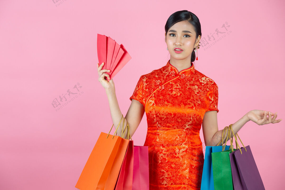 女性美丽的亚洲女人快乐的微笑和购物在中国新年的粉红色背景年空白手势