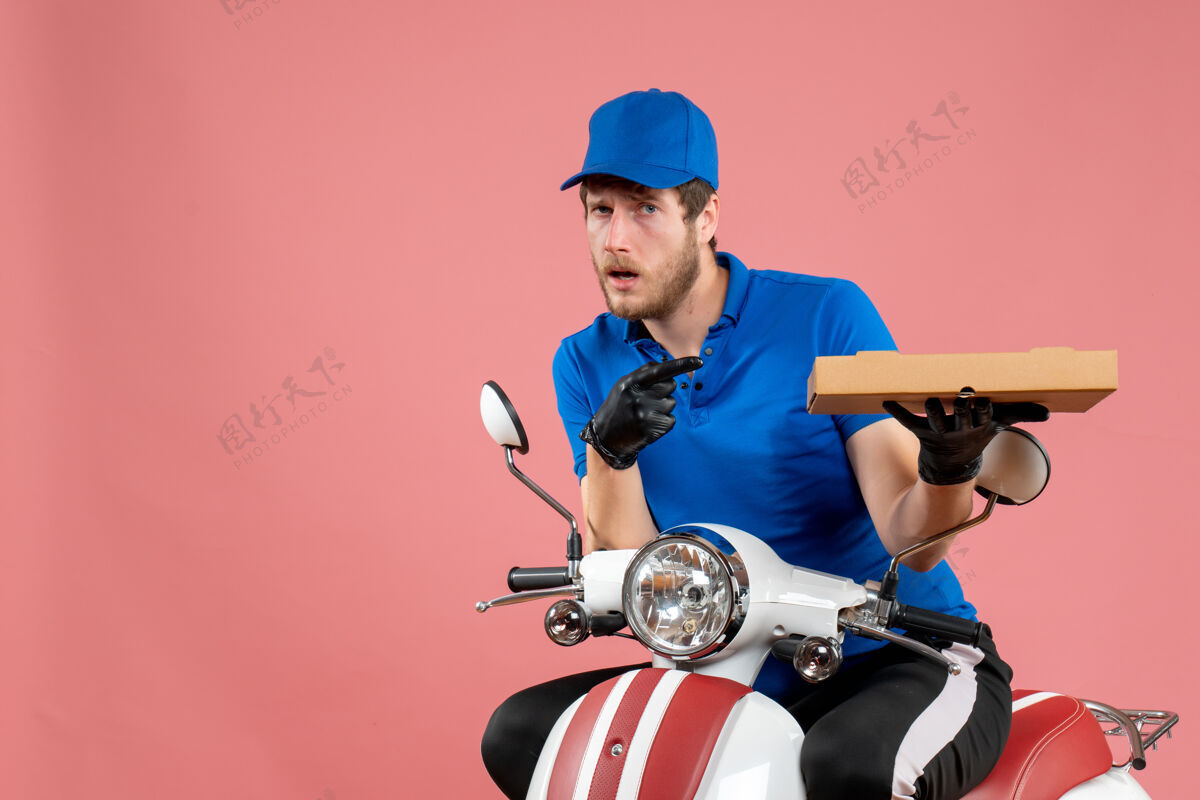 举行正面图男性信使坐在自行车上 拿着粉红色的比萨饼盒工人人盒子