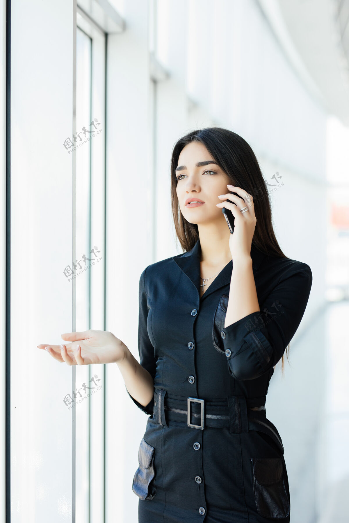 观看后视图：年轻工人用手机说话 望着窗外女员工有业务电话 晚上在工作场所忙碌成人说话智能