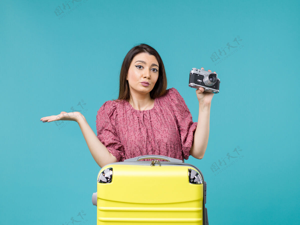 人正面图度假中的年轻女子在蓝色背景上用相机拍照旅行海上旅行女子出国度假成人年轻女子微笑