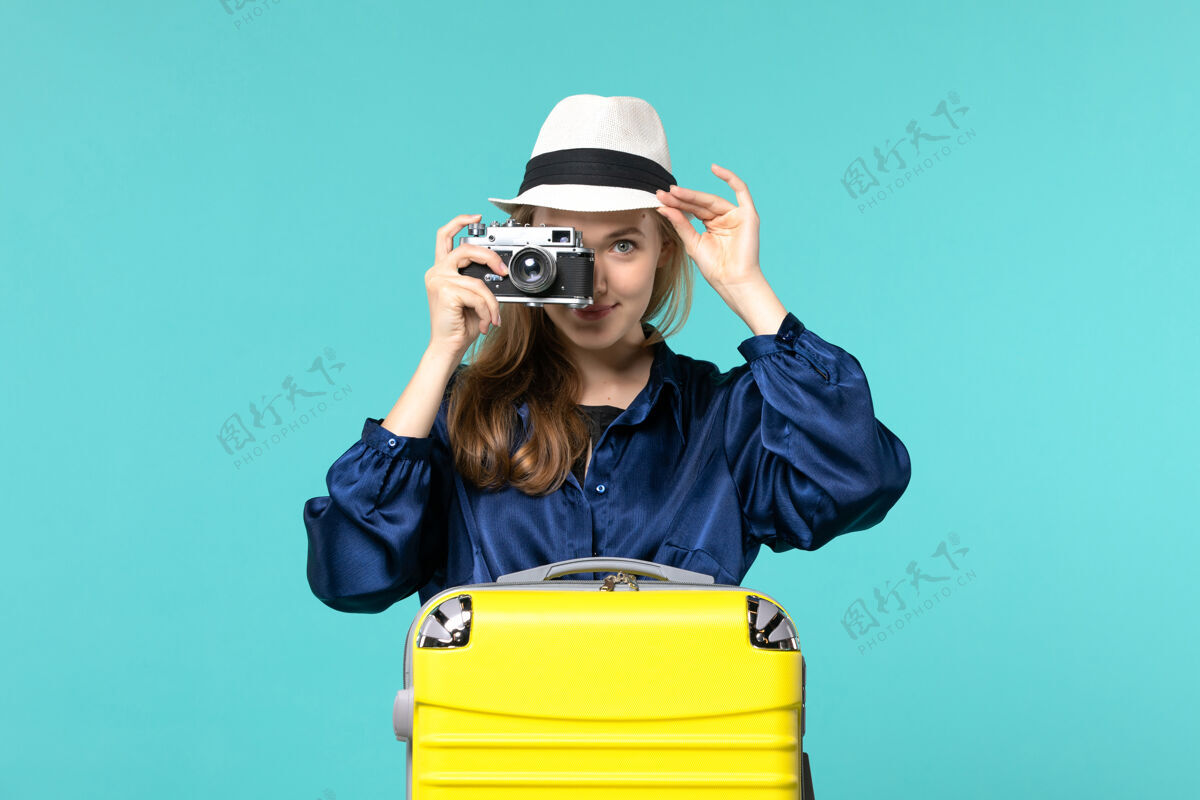 旅行前视图年轻女子手持相机 在蓝色背景的女子海上旅行飞机上拍照持有微笑照片