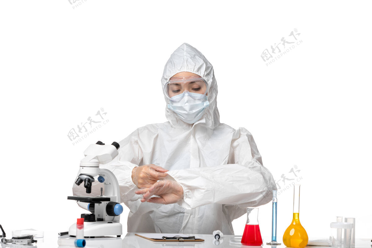 专业正面图年轻女医生穿着防护服 戴着口罩 因为白色背景上坐着柯维德病毒大流行飞溅口罩医生大流行