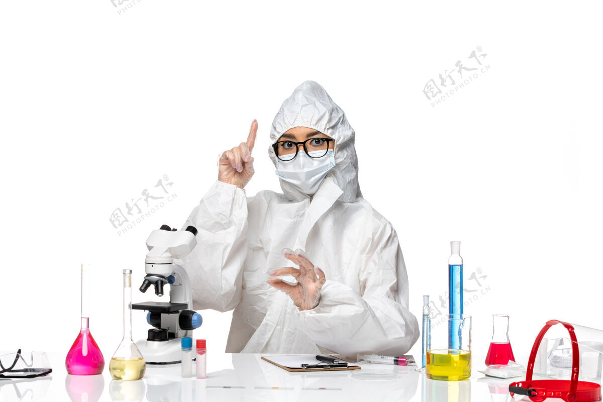 病毒正面图穿着特殊防护服的年轻女化学家坐在白色背景病毒实验室里工作-化学特殊外套药