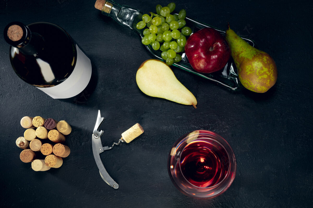 黑暗一瓶和一杯红酒 深色的石头表面有水果广告布里开胃酒