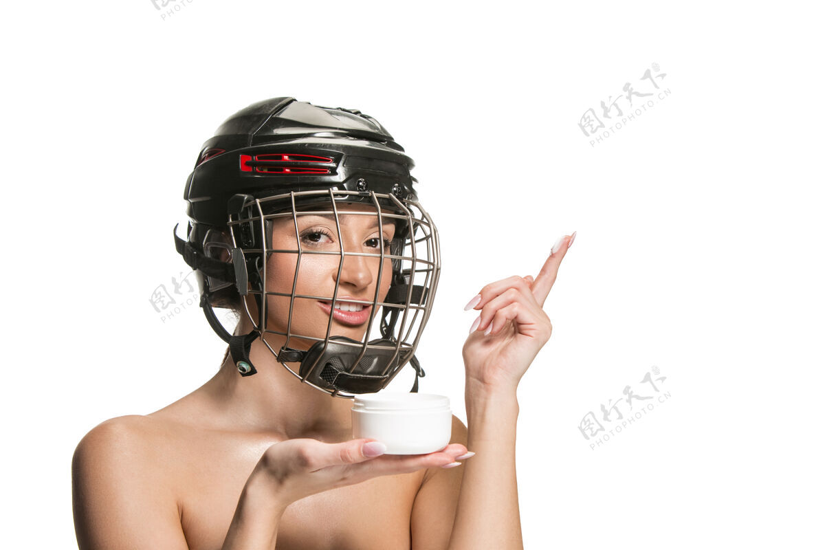 曲棍球戴着头盔和面具的女子冰球运动员在白色的工作室墙上棍棒游戏皮肤护理
