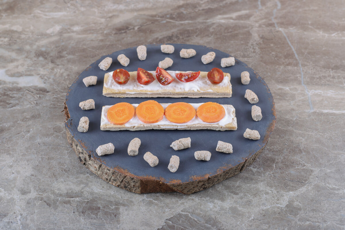 风味胡萝卜片 西红柿面包片 面包屑包在木板上 大理石表面健康年糕梨