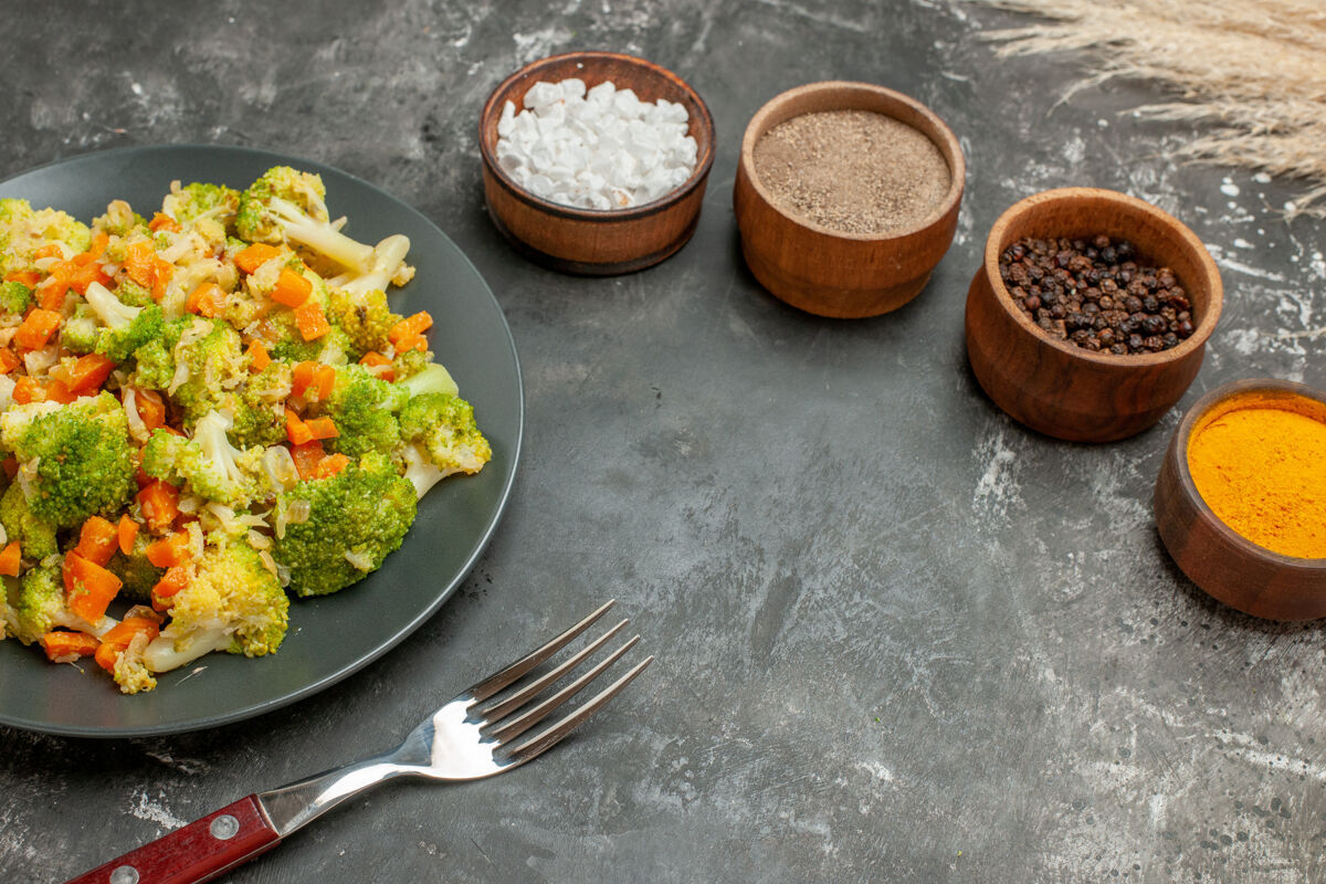 肉在棕色的碗和蔬菜沙拉和叉子在灰色的桌子上设置不同的香料俯视图餐桌晚餐午餐