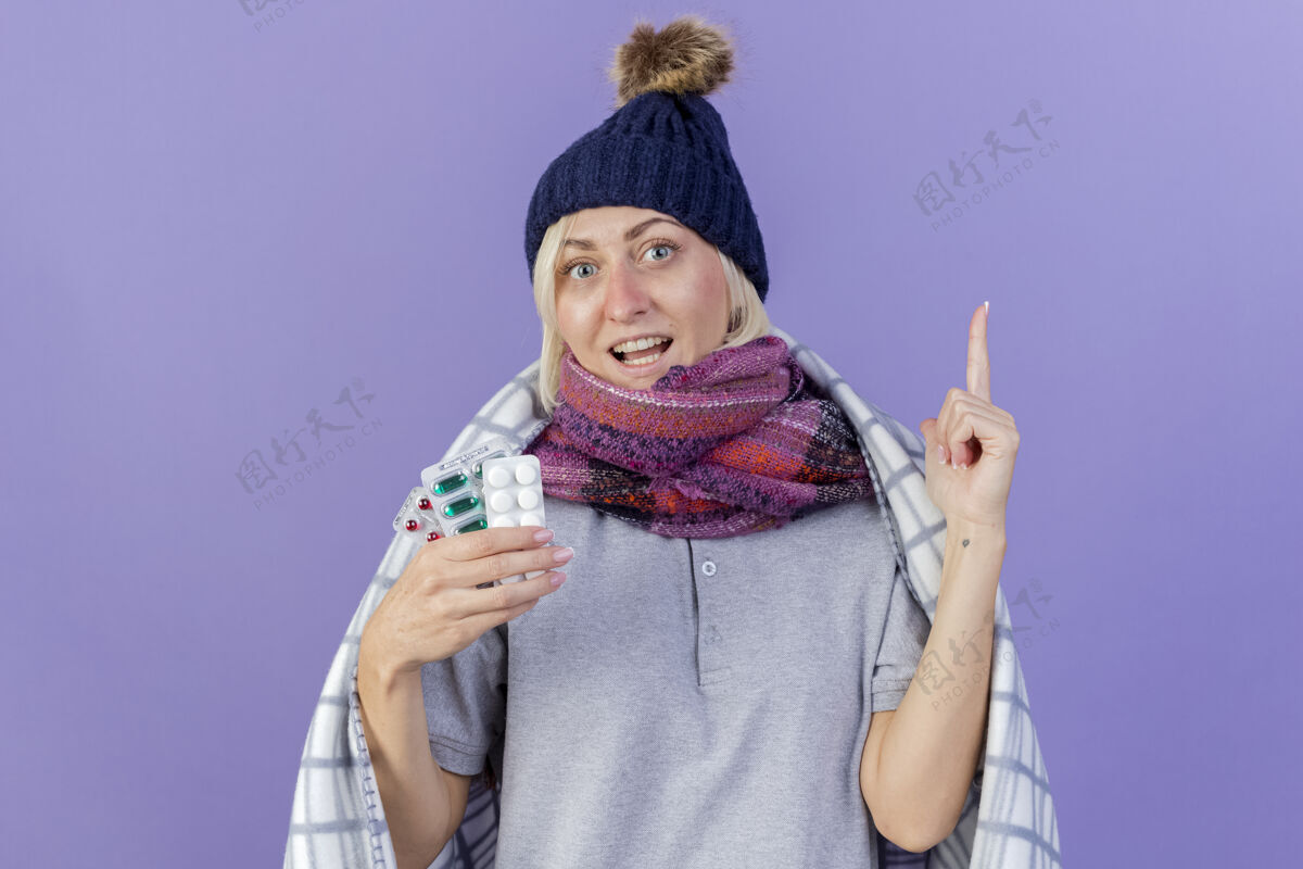 年轻快乐的年轻金发病斯拉夫妇女戴冬季帽子指尖格子药片