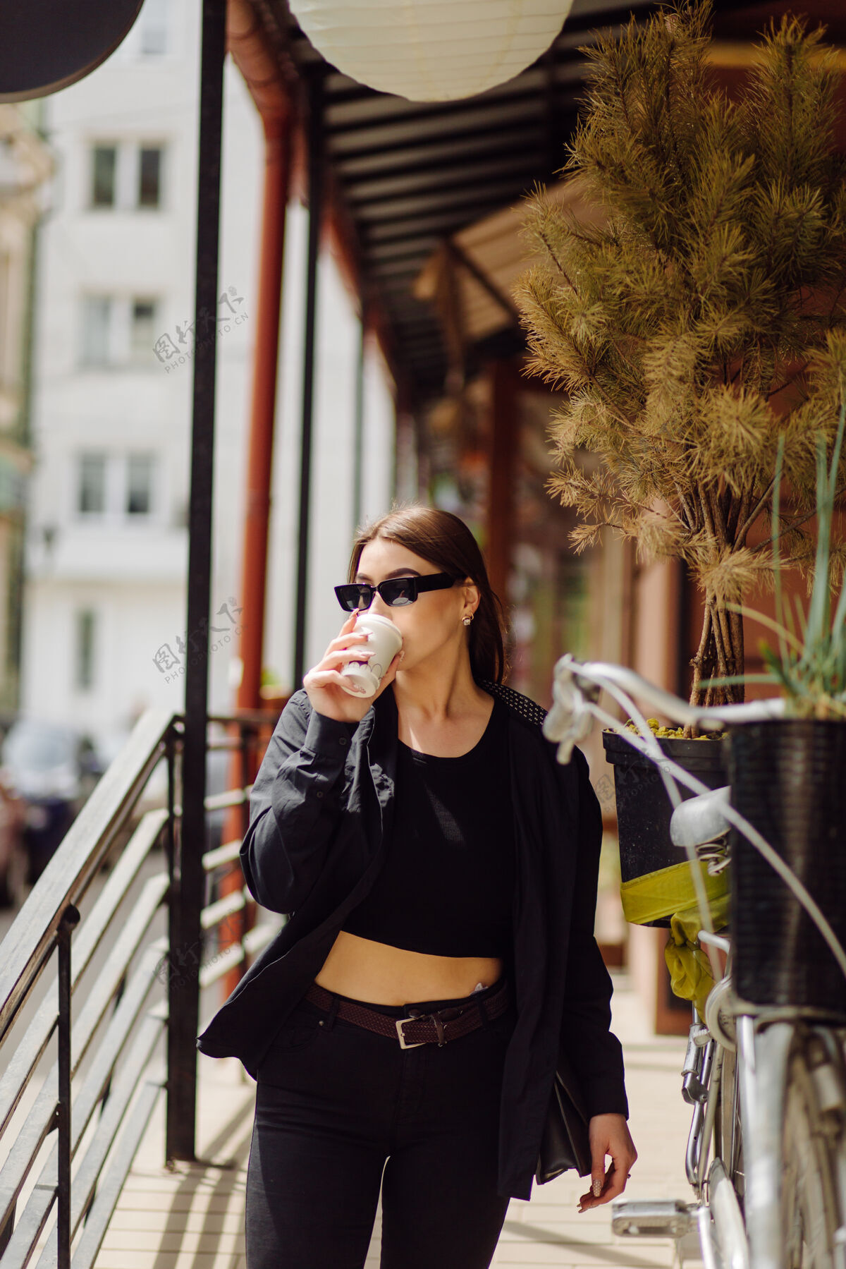 女性户外生活写真迷人的黑发女孩喝咖啡 走在城市街道上毛衣城市早晨