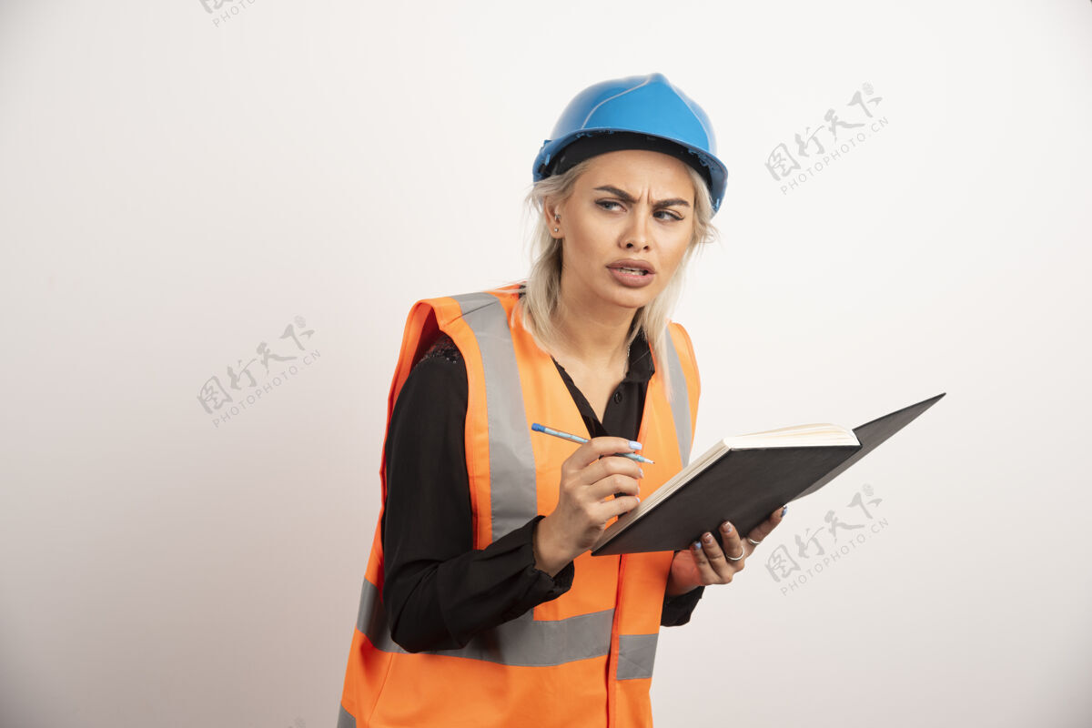 姿势女建筑工人在笔记本上写字高质量的照片头盔笔记本女人