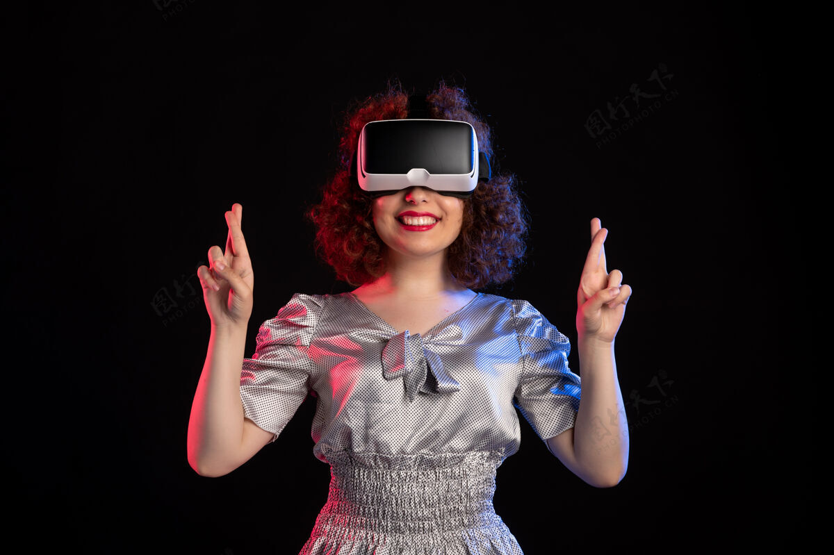 年轻女性年轻女性戴着虚拟现实耳机在黑暗的表面视觉现实黑色