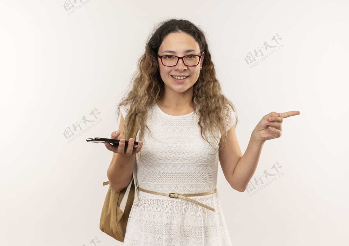 指着面带微笑的年轻漂亮女学生戴着眼镜背着书包拿着手机指着隔离在墙上的一侧包人壁板
